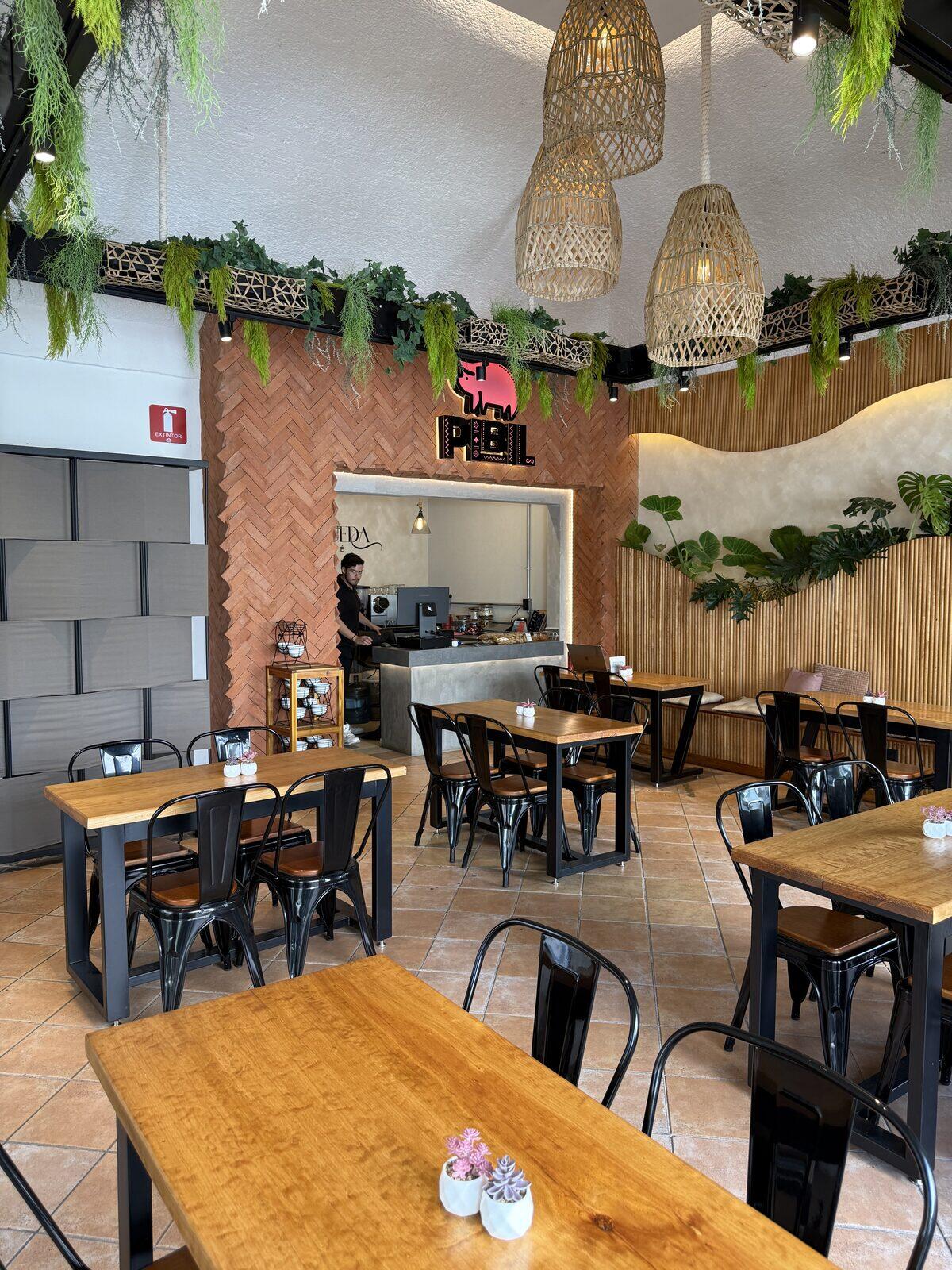 Interior de Pibil Restaurante con letrero de neón rosa y plantas colgantes